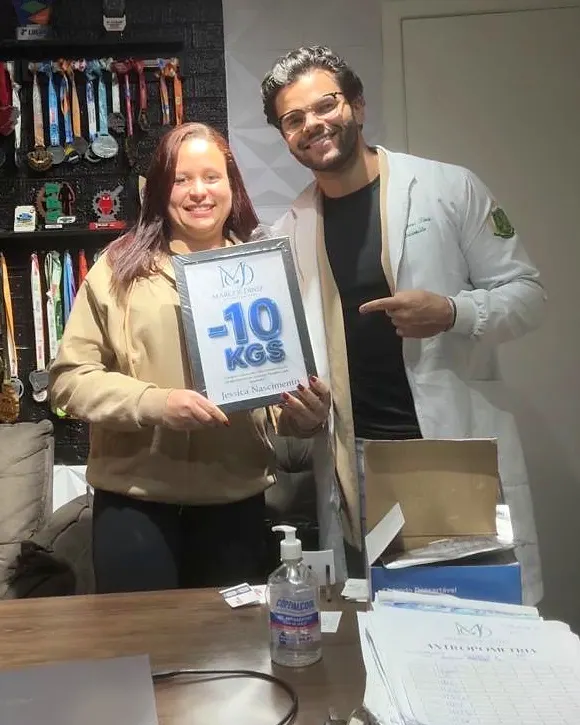 Paciente do Dr. Marcos Diniz recebendo uma placa de resultado