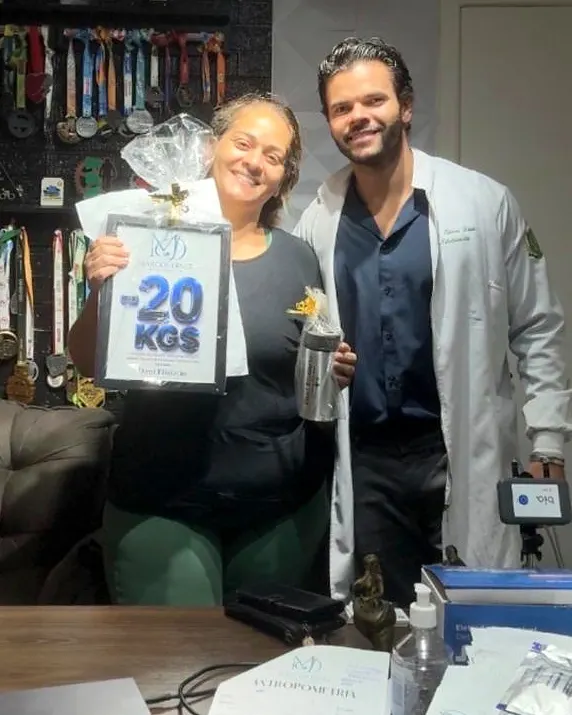 Paciente do Dr. Marcos Diniz recebendo uma placa de resultado