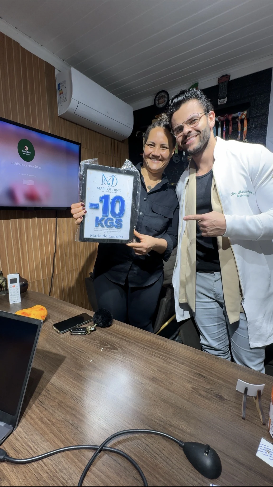 Paciente do Dr. Marcos Diniz recebendo uma placa de resultado
